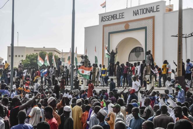 Des supporteurs brandissent des drapeaux nigériens lors d’un rassemblement de soutien à la junte nigérienne, devant l’Assemblée nationale, à Niamey, le 30 juillet 2023. 